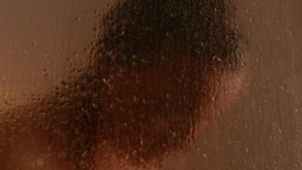 Woman's head standing behind a fogged up showerscreen 